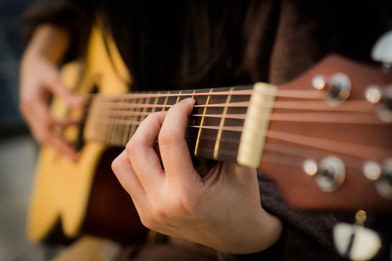 Person playing guitar, representing engaging musical activities